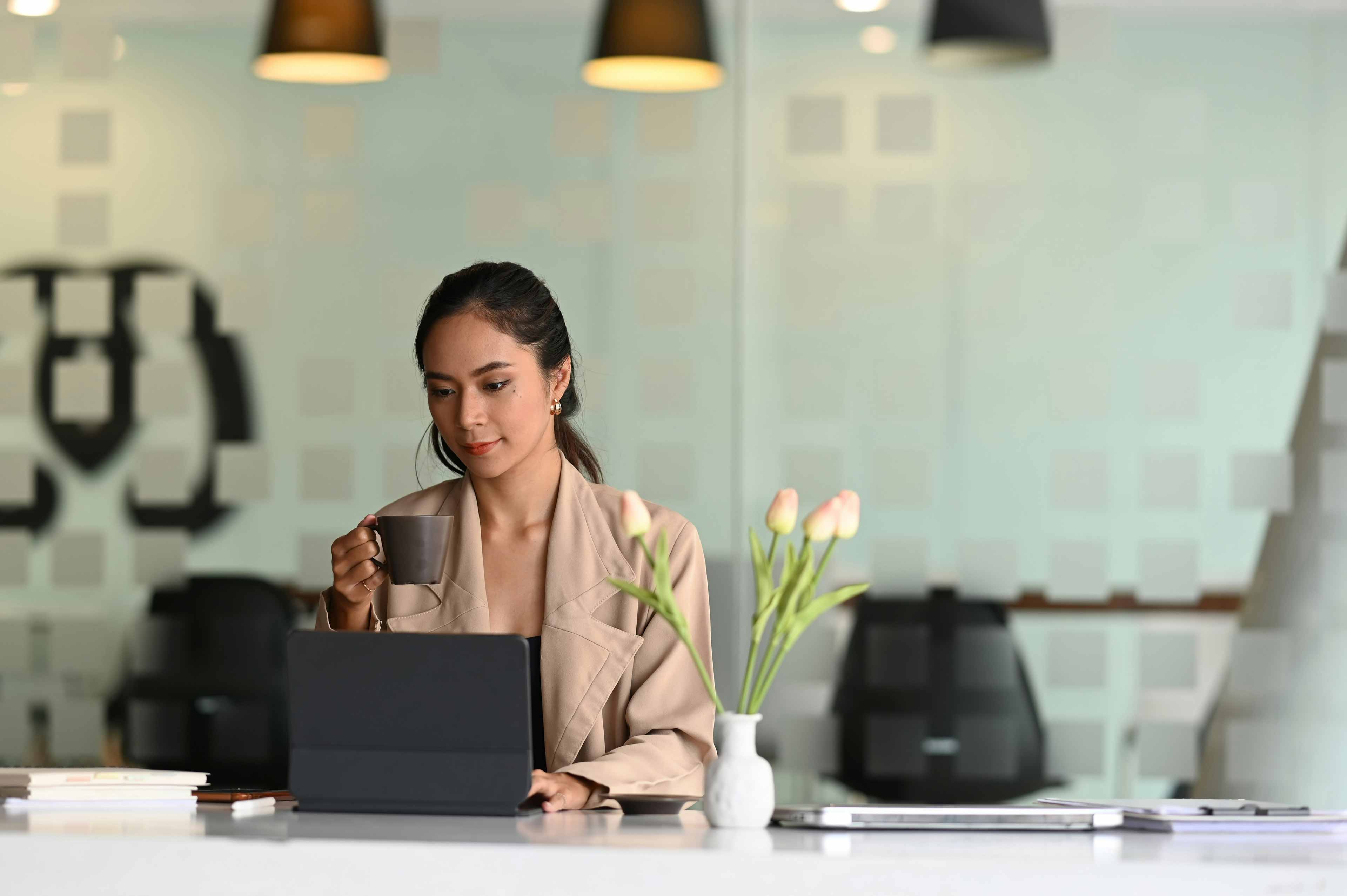 lady working on her computer whily having coffee